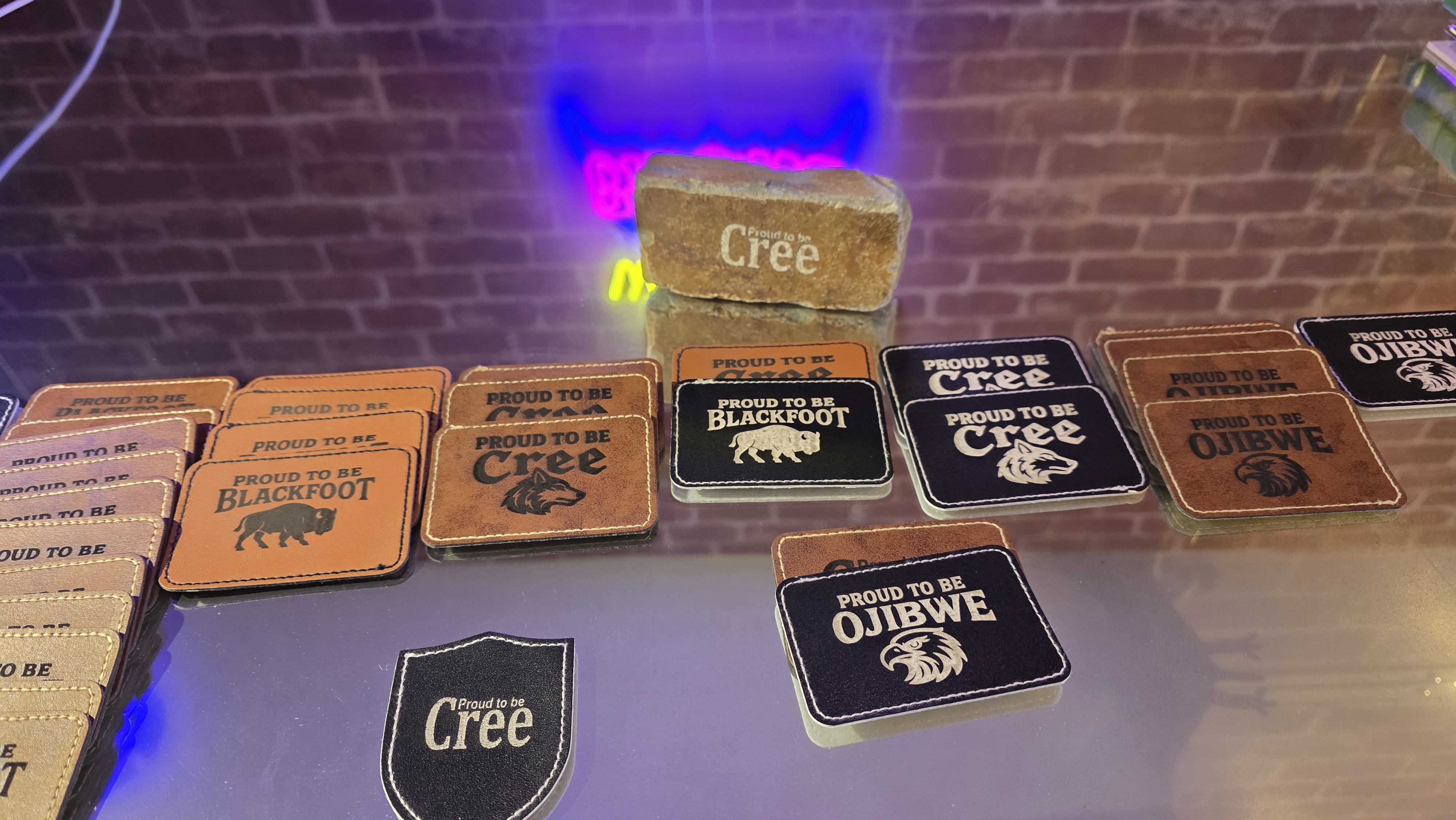 Laser-engraved hat patches arranged on glass, studio lighting